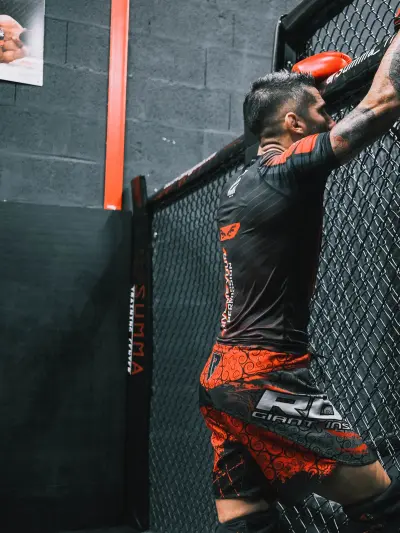 Combattant aux gants rouges contre la cage MMA du Summa Training Center